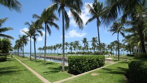 A well-maintained grassy area with palm trees and a pathway leading to a body of water. - Marathon Townhome | Boat Slip + Pool | Gulf Access (Marathon)