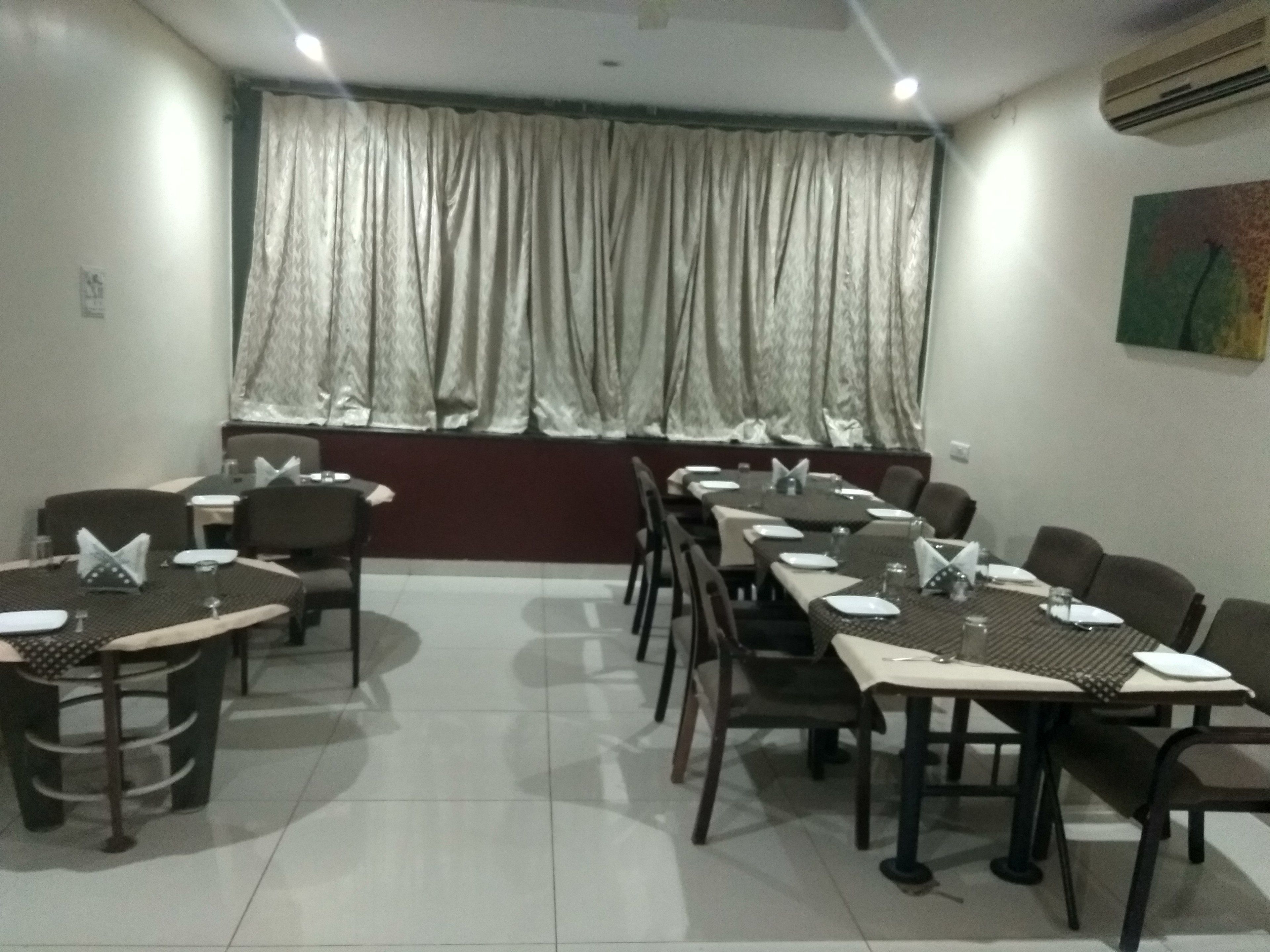 A conference room with tables set for meetings, a large window with curtains, and an air conditioning unit on the wall.