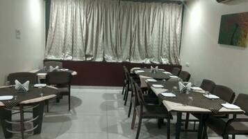 A conference room with tables set for meetings, a large window with curtains, and an air conditioning unit on the wall.