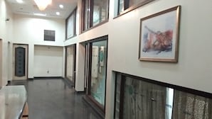 A corridor with a glass partition, a framed artwork on the wall, and a ceiling light fixture.