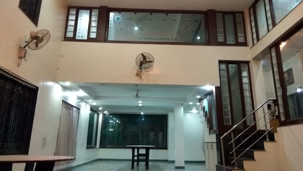 A spacious hall with a high ceiling, multiple fans, and a chandelier.