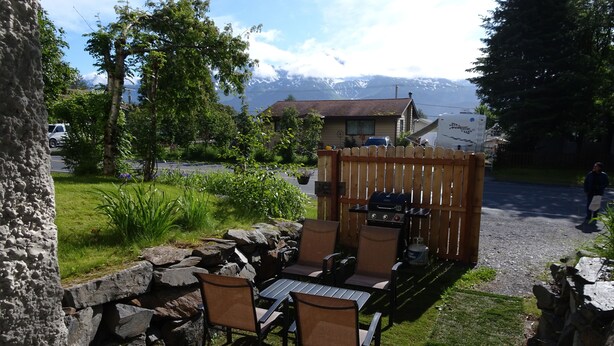 An outdoor patio with a table and chairs, surrounded by a stone wall and a wooden fence.