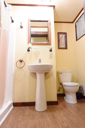 Casa de banho com lavatório assentado, sanita e espelho sobre o lavatório.