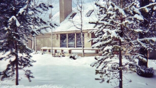Een huis bedekt met sneeuw, met een groot raam en schoorsteen.