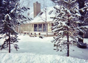 Een huis bedekt met sneeuw, met een groot raam en schoorsteen.