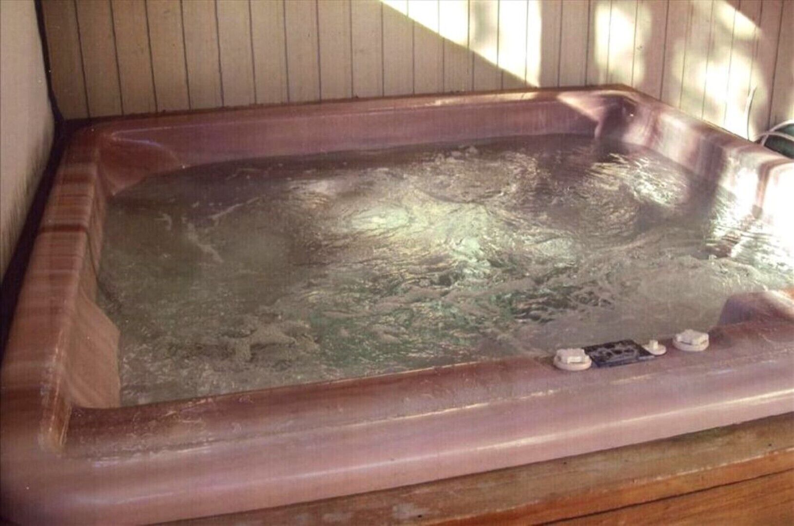 Una bañera de hidromasaje con estructura y suelo de madera a su alrededor.