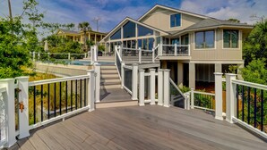 Une maison à deux étages dotée d’une terrasse en bois, d’une piscine et d’un patio couvert.