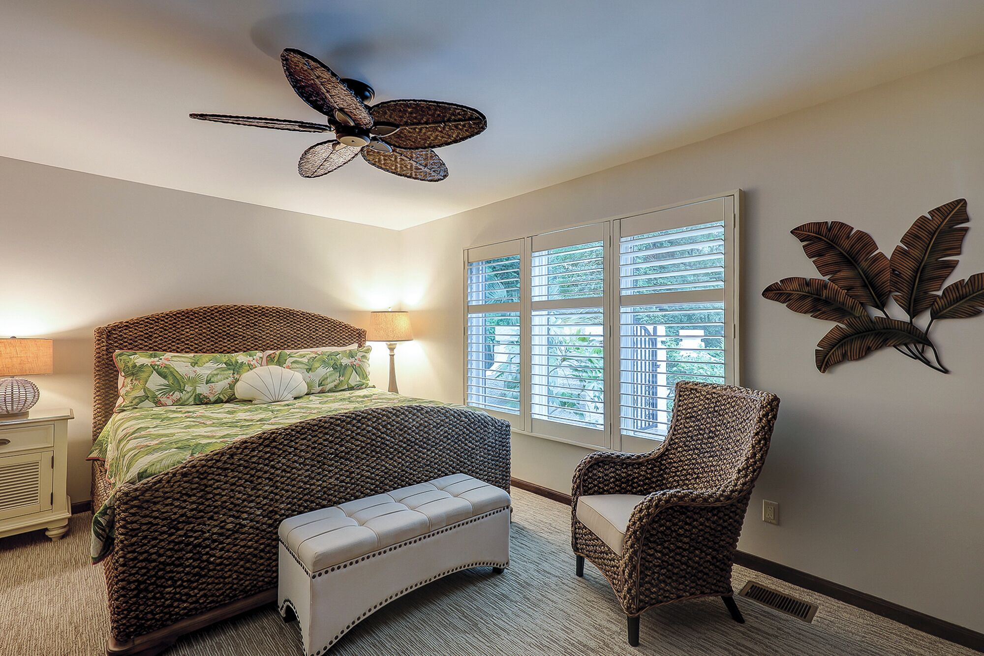 A bedroom with a bed, a bench, a chair, a ceiling fan, and a window with blinds.