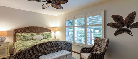 A bedroom with a bed, a bench, a chair, a ceiling fan, and a window with blinds.