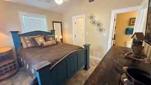 Un dormitorio con una cama grande, un aparador, un espejo y una puerta que da a otra habitación.
