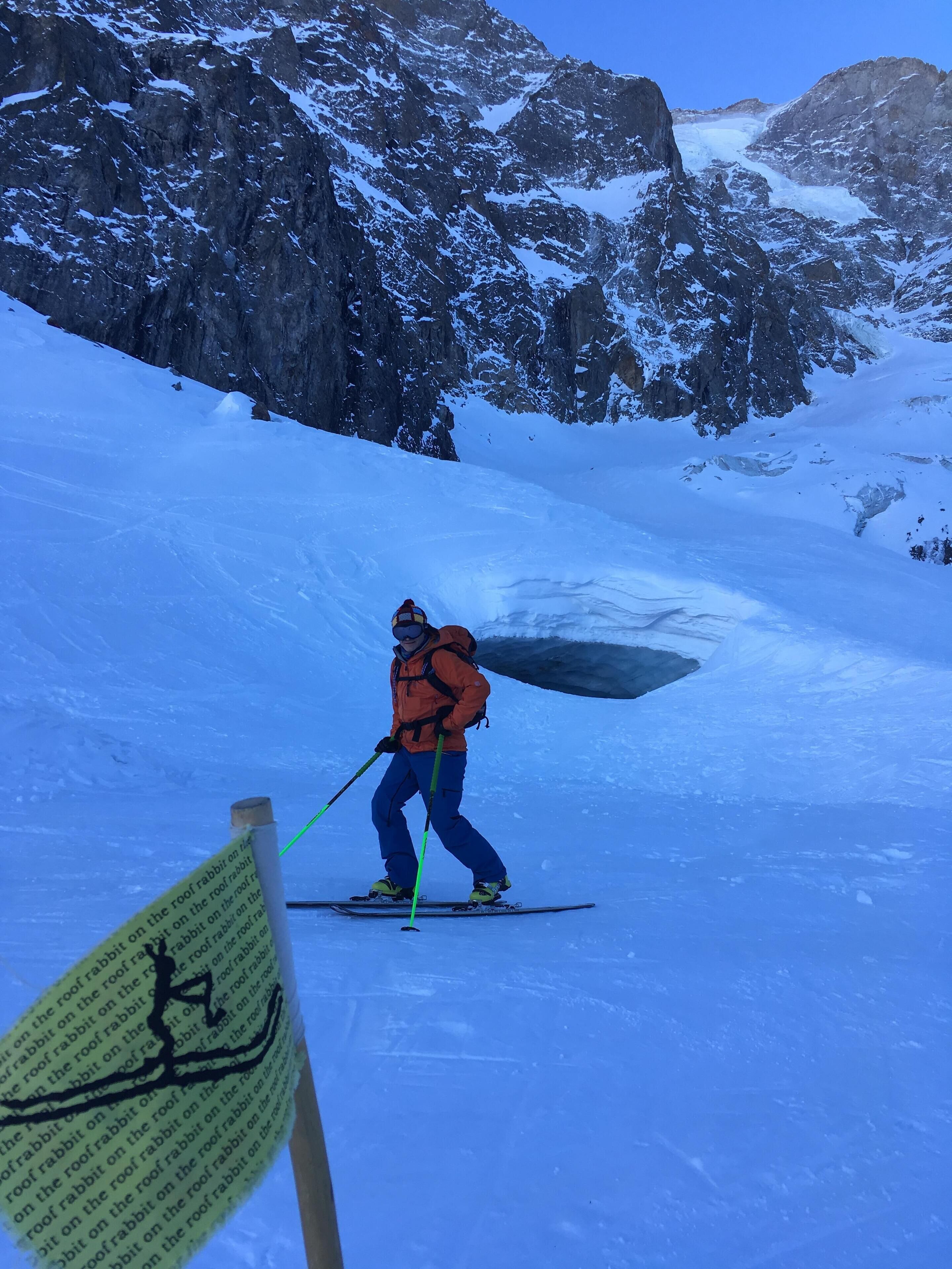 A person skiing down a snowy slope with a sign in the foreground.