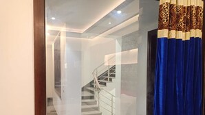 A modern interior with a staircase, a glass partition, and a blue curtain. - JJK Rukmini Vilas Hotels and Banquets (Muzaffarpur)