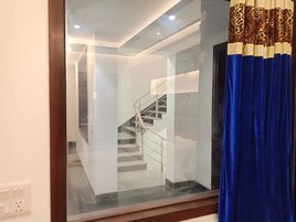 A modern interior with a staircase, a glass partition, and a blue curtain.