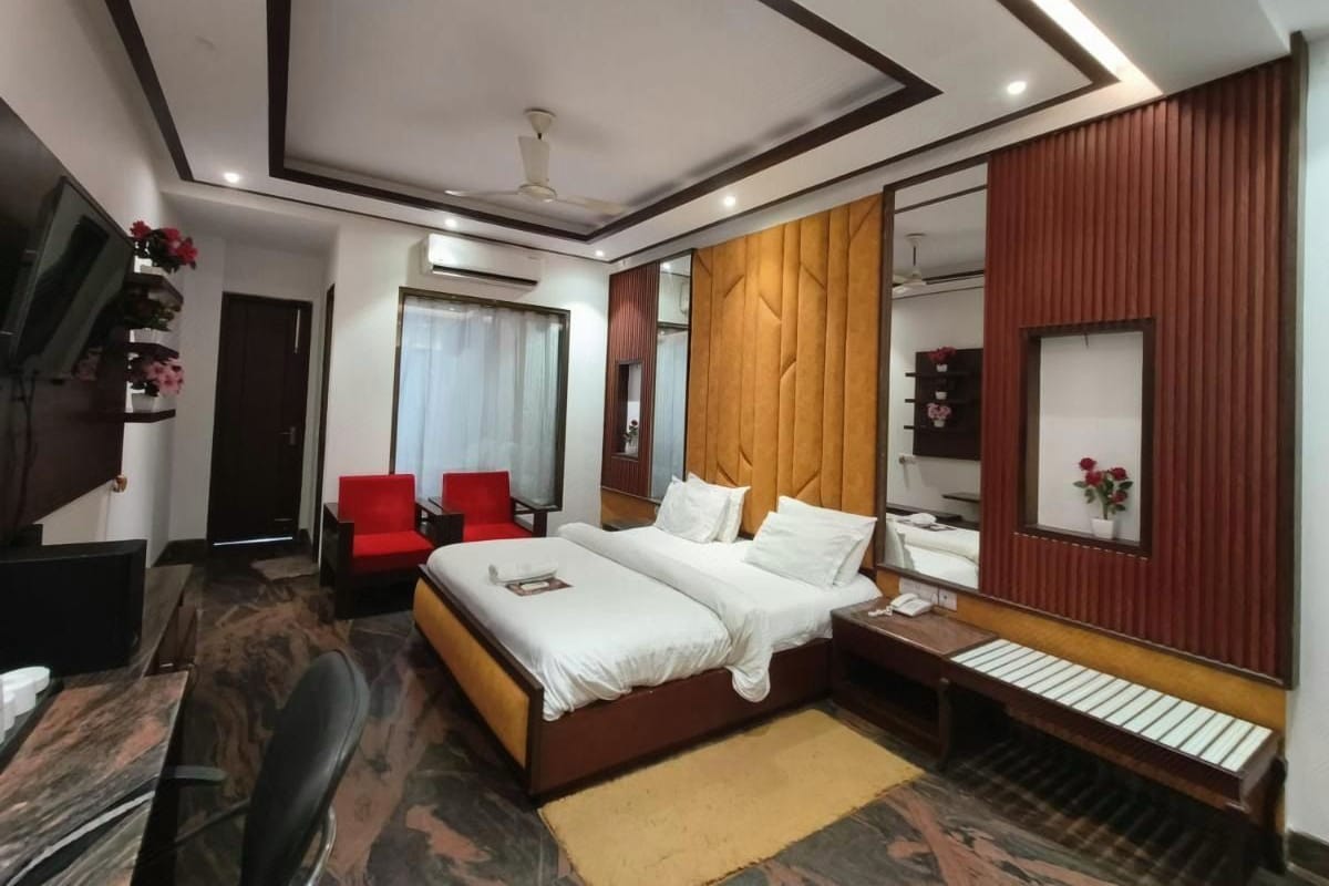 Ein Hotelzimmer mit einem Bett, einem Schreibtisch, einem Stuhl, einem Fernseher und einem Spiegel.