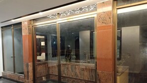 A hotel lobby with a modern design, featuring a glass entrance, marble columns, and a clean, polished floor. - JJK Rukmini Vilas Hotels and Banquets (Muzaffarpur)
