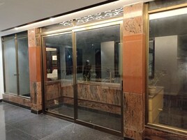 A hotel lobby with a modern design, featuring a glass entrance, marble columns, and a clean, polished floor.