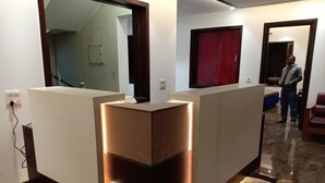 A reception area with a modern design, including a reception desk, a large mirror, and a red curtain. - JJK Rukmini Vilas Hotels and Banquets (Muzaffarpur)