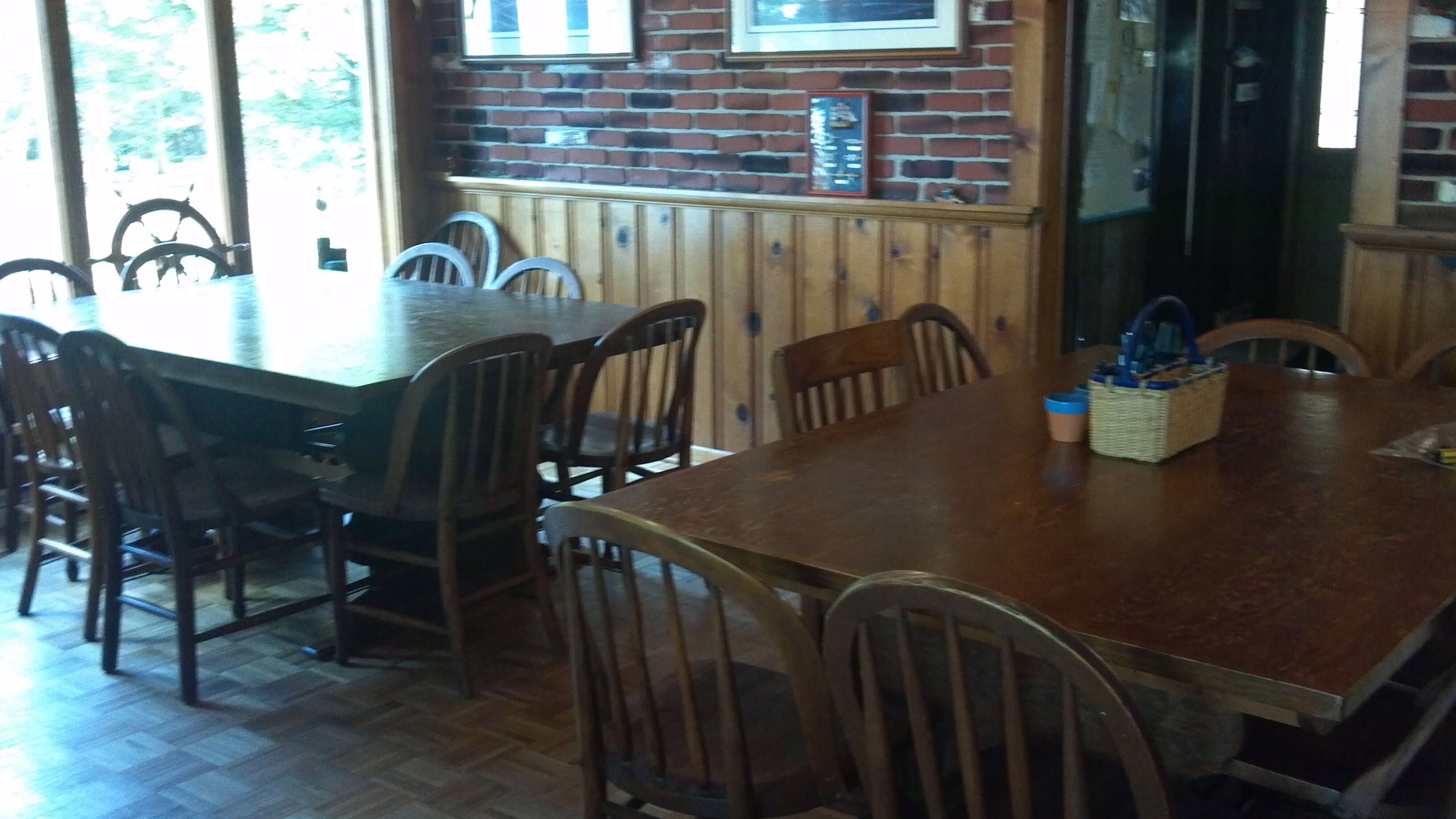Un comedor con una mesa y sillas de madera, una pared de ladrillo con un microondas y una ventana con persianas.
