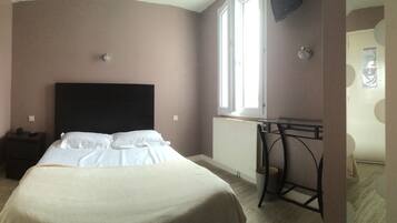 A bedroom with a bed, bedside table, and a window.