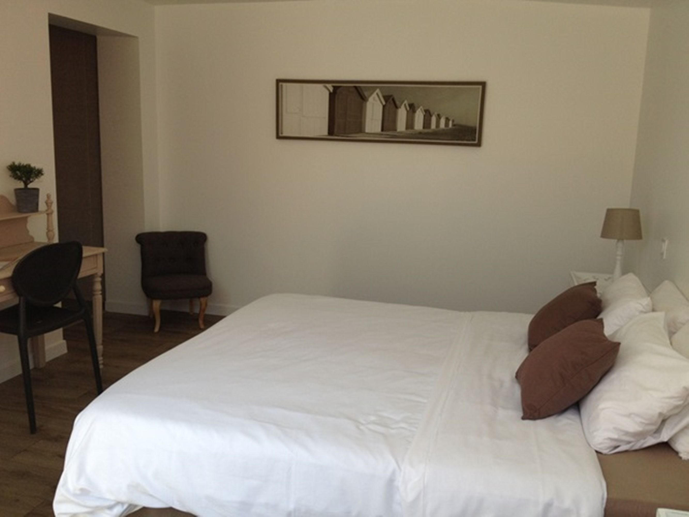 Un cuarto de hotel ordenado con una cama grande, un escritorio, una silla y una lámpara.