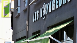 Hotel llamado "LES VOYAGEURS" con toldo verde y entrada visible.