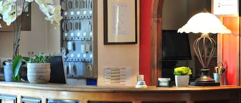 A reception desk with a clock, key hooks, framed menu, and decorative items.