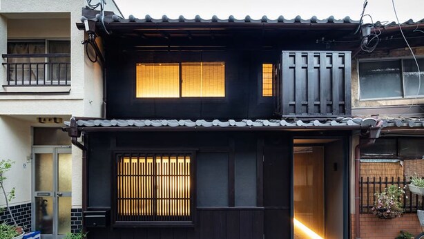 Ein traditionelles japanisches Haus mit dunkler Fassade, einem Ziegeldach und einem Holztor.
