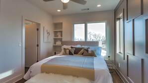 Une chambre à coucher avec un lit, un ventilateur de plafond, une fenêtre et une porte.