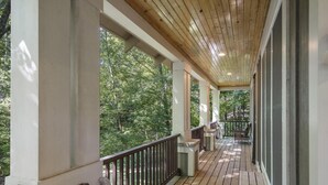 Eine überdachte Veranda mit Holzgeländern und Blick auf einen bewaldeten Bereich.