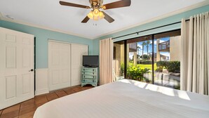 A bedroom with a large bed, a ceiling fan, a television on a dresser, and a sliding glass door leading to a balcony. - Discover Blue Surf 9, Pet-Friendly 2BR Townhouse Beach Service Included Miramar Beach! (Destin)