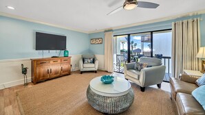A living room with a flat-screen TV, wooden cabinet, two armchairs, a round coffee table, and a ceiling fan. - Discover Blue Surf 9, Pet-Friendly 2BR Townhouse Beach Service Included Miramar Beach! (Destin)