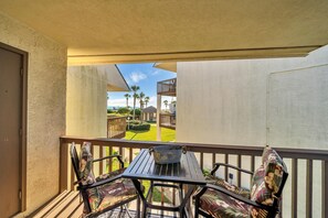 A balcony with a table and chairs, overlooking a well-maintained lawn and a building with a wooden deck. - Discover Blue Surf 9, Pet-Friendly 2BR Townhouse Beach Service Included Miramar Beach! (Destin)