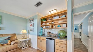 A compact kitchen with wooden cabinets, a built-in dishwasher, and a countertop with decorative items. - Discover Blue Surf 9, Pet-Friendly 2BR Townhouse Beach Service Included Miramar Beach! (Destin)