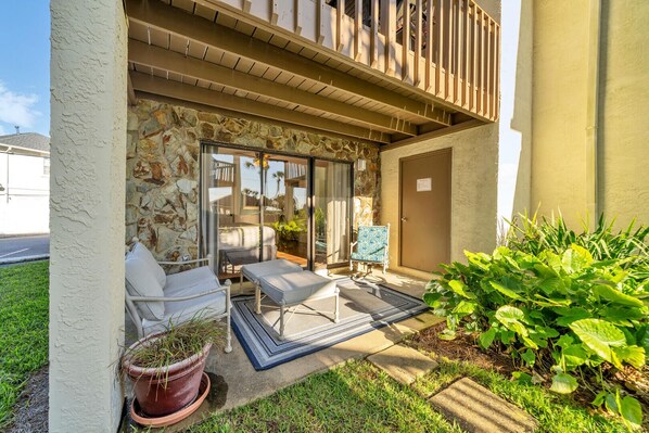 A covered outdoor seating area with a stone wall, a door, and a potted plant. - Discover Blue Surf 9, Pet-Friendly 2BR Townhouse Beach Service Included Miramar Beach! (Destin)