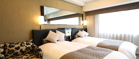 Une chambre d’hôtel avec deux lits, un canapé, un grand miroir et un lustre.