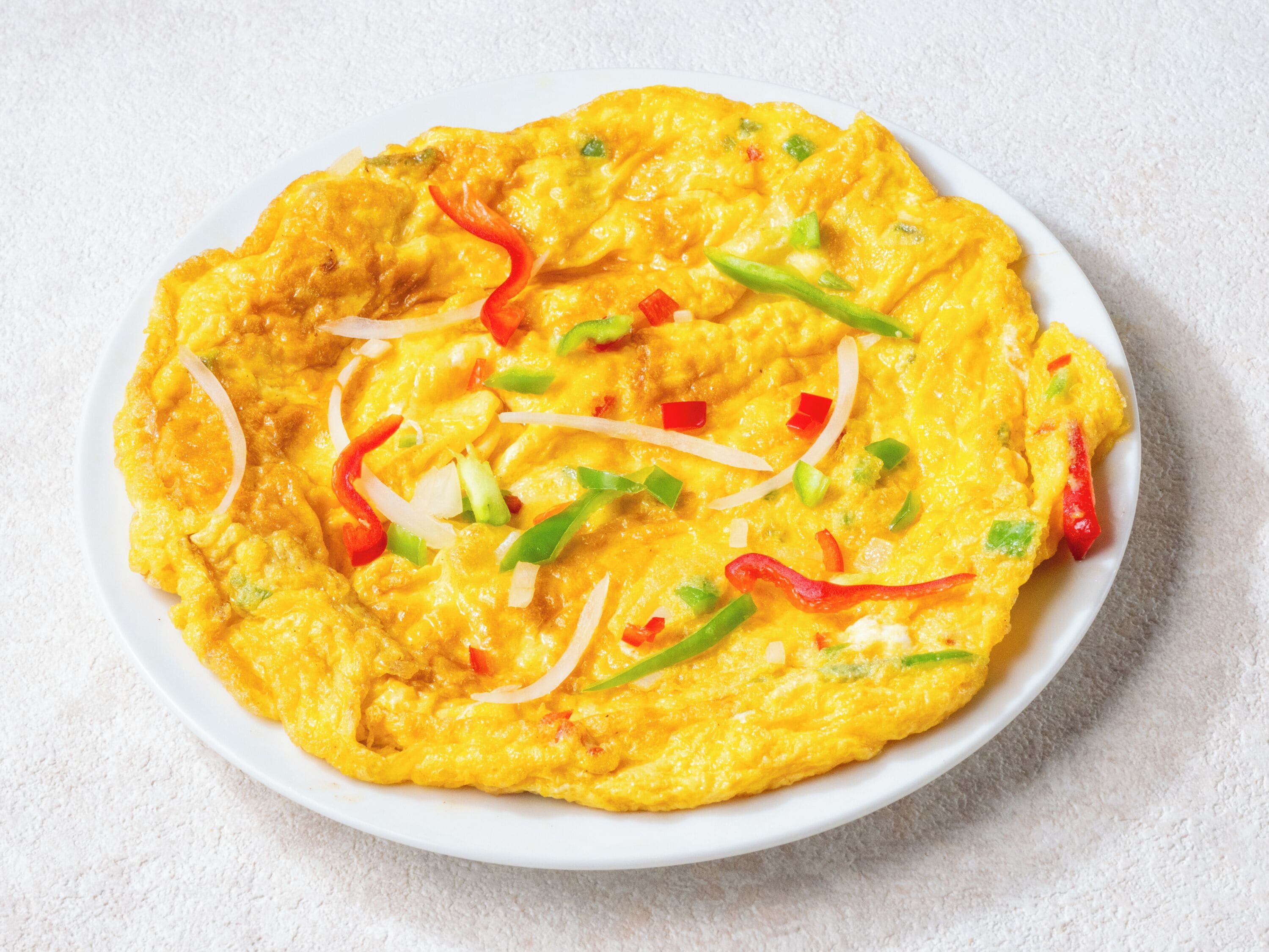 A plate of scrambled eggs with red and green bell peppers and onions.