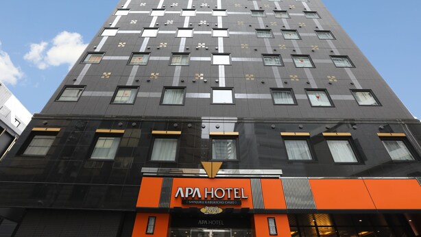 A tall hotel building with a modern design, featuring a prominent orange sign for APA HOTEL. - APA Hotel Shinjuku Kabukicho Chuo (Tokyo)