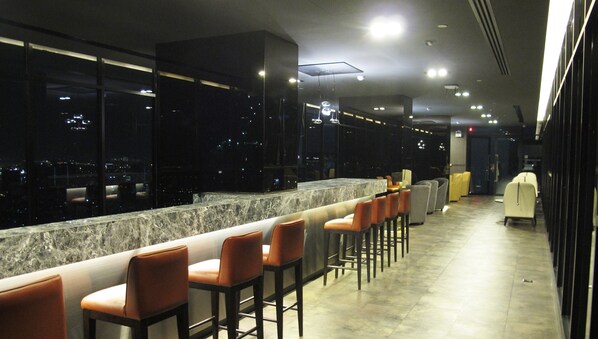 A bar area with a marble counter and multiple bar stools.