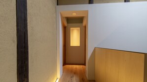 Un couloir étroit doté d’un plancher en bois et d’un luminaire encastré.