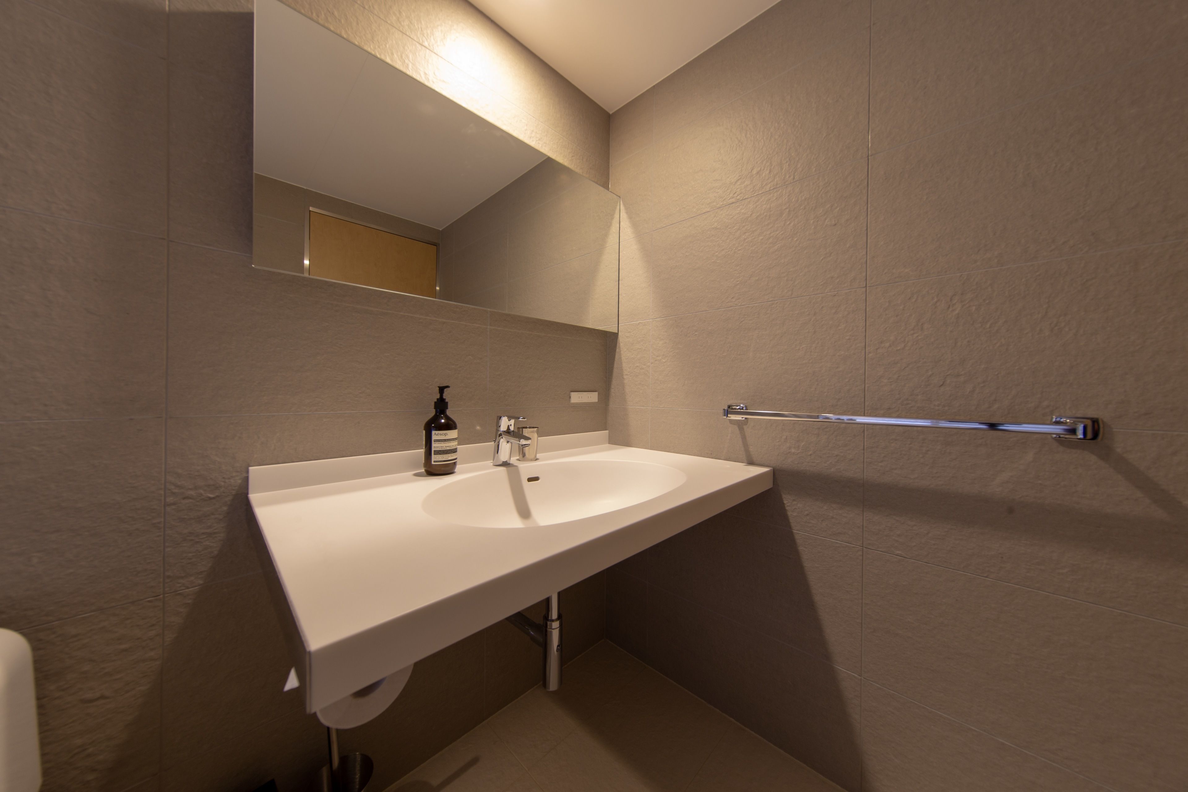 A modern bathroom with a white sink, a mirror, and a towel rack.