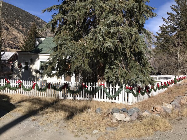 A house with a white picket fence, decorated with red bows and green garlands.