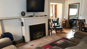 En stue med pejs, et tv monteret over den, og en stor sofa.