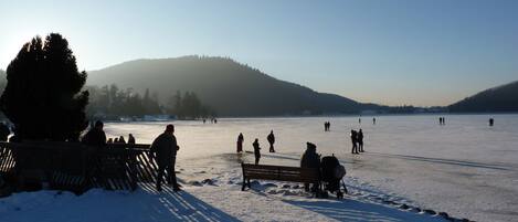 A frozen lake with people walking and sitting on benches.