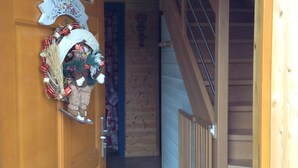 A wooden door with a Christmas wreath and a welcome sign. A staircase leads to an upper level. - Charming 4* chalet with panoramic view, south-facing, sleeps 6. (Gérardmer)