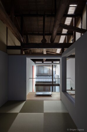 A traditional Japanese room with tatami flooring, a low ceiling with wooden beams, and a sliding door leading to another space.