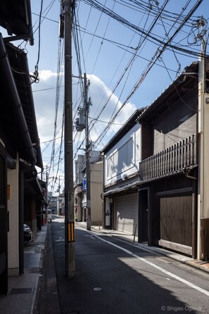A narrow street with traditional buildings, power lines overhead, and a clear sky.