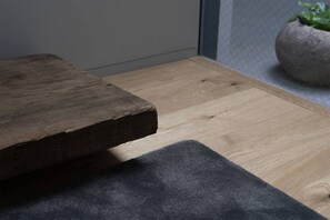 A wooden table with a dark mat on a light wooden floor.