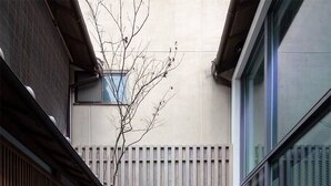 A modern outdoor space with a wooden bench, a black rectangular planter, and a glass wall. - Residence Jo 15 Karasuma shijyo (Kyoto)