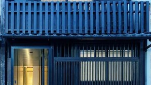 A building with a dark facade, a gated entrance, and a visible interior hallway. - Residence Jo 15 Karasuma shijyo (Kyoto)