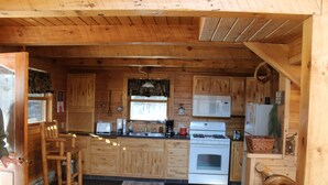 A wooden cabin-style kitchen with wooden cabinets, a stove, and a microwave. - Reid's Hidden River Getaway (Luther)
